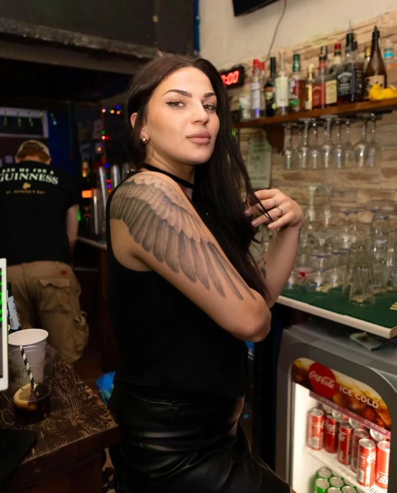Maria behind the bar at the Classic, whiskey shelf and glassware behind