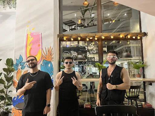 Three friends posing in front of the Sports Bar mural