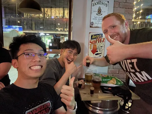 Three regulars with drinks, thumbs up