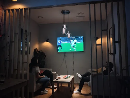 Private viewing room with a match on the screen, couches on either side, low lighting