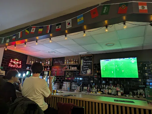 Match on the screen above the bar, flags overhead, regulars watching
